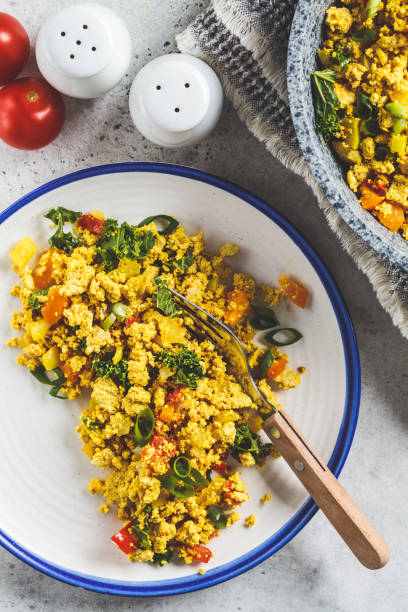 istock Tofu scramble with vegetables in a white plate, top view. Vegan Alternative fried eggs. 1178043207