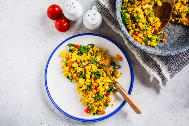 istock Tofu scramble with vegetables in a white plate, top view. Vegan Alternative fried eggs. 1178043221