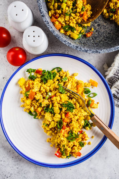 istock Tofu scramble with vegetables in a white plate, top view. Vegan Alternative fried eggs. 1178043244