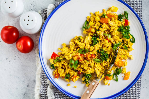 istock Tofu scramble with vegetables in a white plate, top view. Vegan Alternative fried eggs. 1178043321
