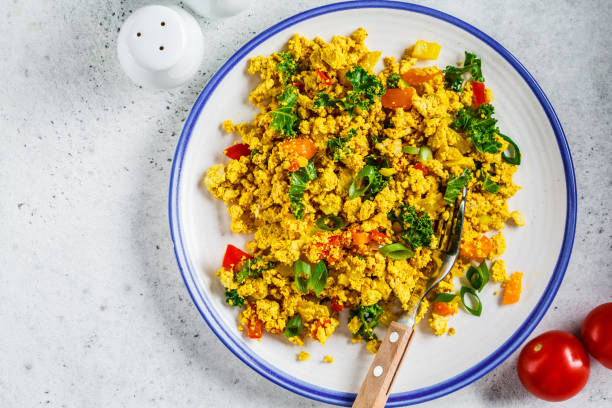 istock Tofu scramble with vegetables in a white plate, top view. Vegan Alternative fried eggs. 1178043334
