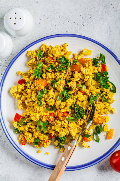 istock Tofu scramble with vegetables in a white plate, top view. Vegan Alternative fried eggs. 1178043347