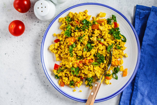 istock Tofu scramble with vegetables in a white plate, top view. Vegan Alternative fried eggs. 1178043365