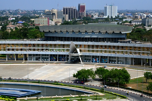 Lomé, Togo: The Congress Palace (Palais de Congrès) on Independence Square - large Brasilia style government building used for multiple purposes: exhibition hall, convention center, parliament, National museum.... -  Place de l'Independance, Quartier Administratif - city skyline in the background, with three bank towers: BOAD, BIDC, BTCI.