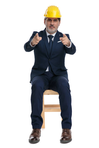 istock businessman with safety helmet sitting and pointing forward 1178044559