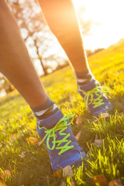 Image of human legs in sportshoes running down green spring grass.