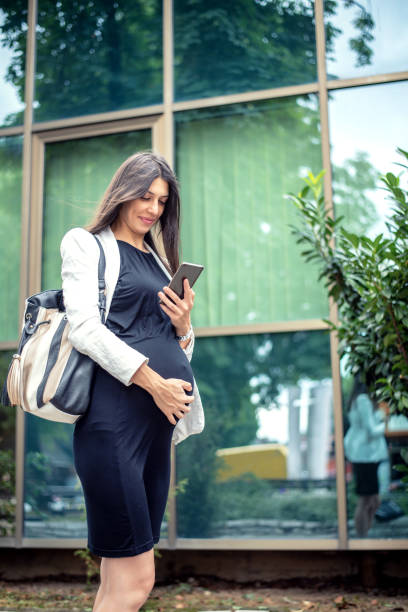 istock Pregnant business woman walking while using smartphone 1178046866