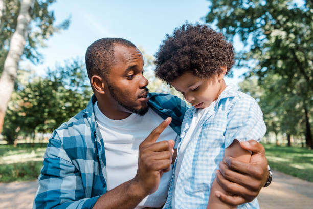 istock handsome father looking at african american sad son while pointing with finger 1178048213