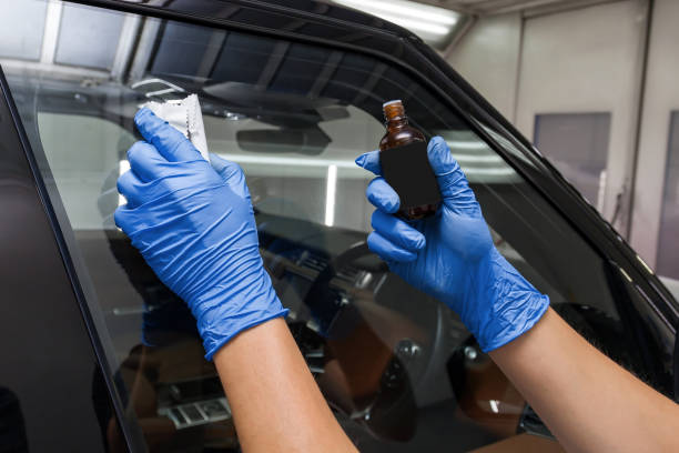 The process of applying a nano-ceramic coating for hydrophobic effect on the car's windows by a male worker with a sponge and