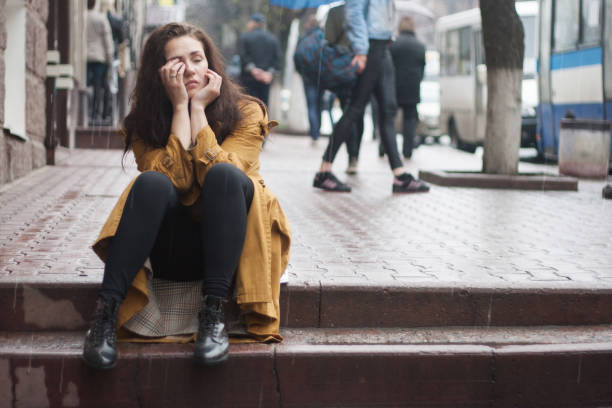 Triste joven sentada al aire libre en otoño en un día lluvioso. - foto de stock