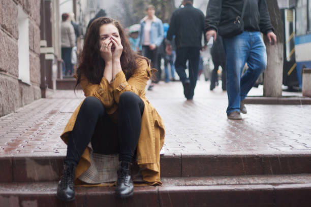 Triste joven sentada al aire libre en otoño en un día lluvioso. - foto de stock