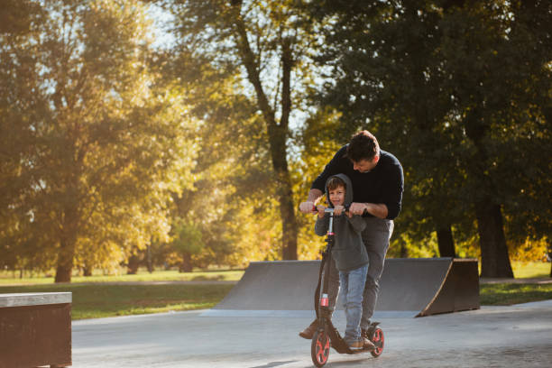 istock Little boy riding a push scooter with his dad 1178051903
