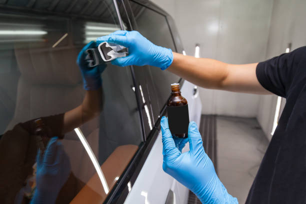 der prozess der anwendung einer nano-keramik-beschichtung für hydrophobe wirkung auf die fenster des autos durch einen männlichen arbeiter mit einem schwamm und - glass car repairing auto repair shop stock-fotos und bilder