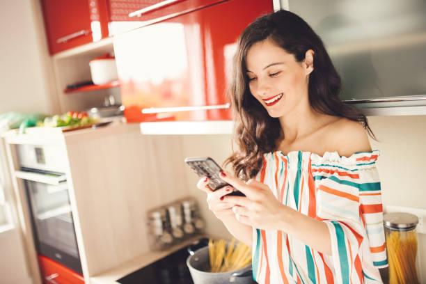 istock Woman holding mobile phone in her kitchen 1178055031