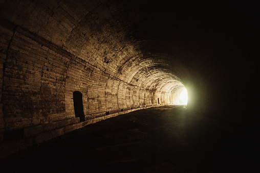 Light at the end of the tunnel concept - An old, dark tunnel leading to light
