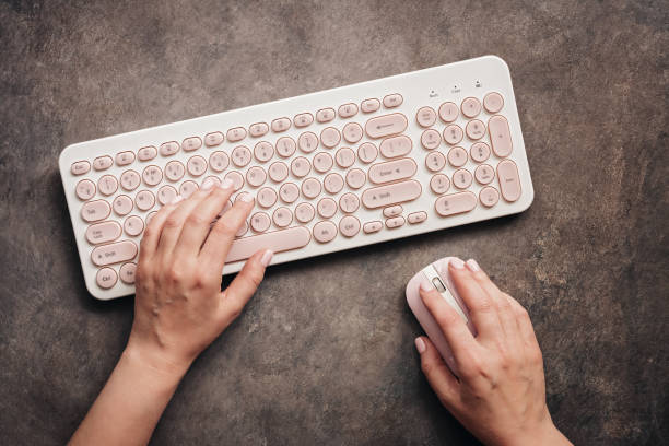 istock Female workspace. Woman hands, keyboard and mouse on a dark rustic textured table. Flat lay, top view office table desk 1178059748