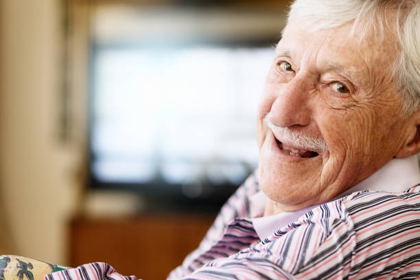 istock Cheerful senior man turns from television, smiling in greeting 1178061077