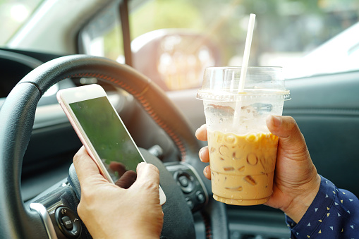 Mujer asiática sosteniendo café helado y teléfono móvil en el coche a la comunicación con los amigos en las felices vacaciones calientes. photo