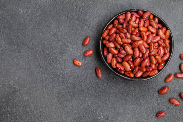 Red kidney beans in a black bowl on grey stone background. Top view. Copy space. Red kidney beans in a black bowl on grey stone background. Top view. Copy space healthy eating red above studio shot stock pictures, royalty-free photos & images