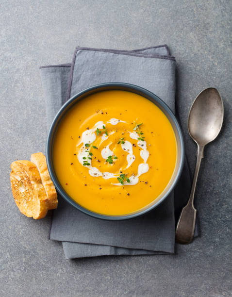 Pumpkin, carrot cream soup in a bowl. Grey background. Top view. Pumpkin, carrot cream soup in a bowl. Grey background. Top view pumpkin soup photos stock pictures, royalty-free photos & images