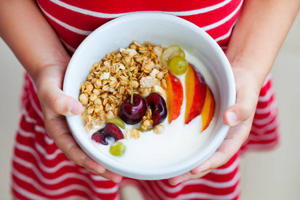 desayuno saludable. muesli con yogur, frutas y bayas en las manos de una niña. - cereal breakfast granola healthy eating fotografías e imágenes de stock