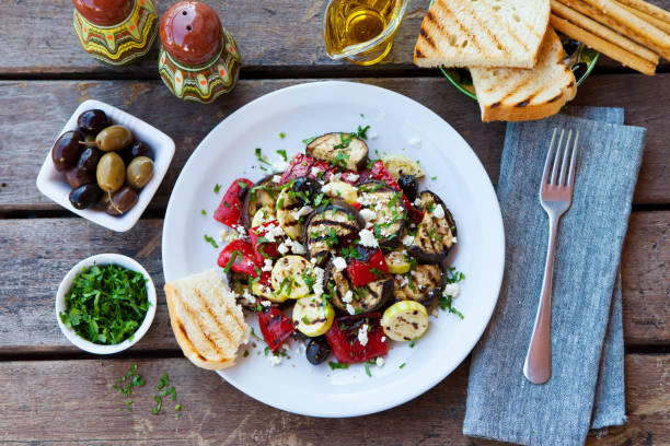 insalata di verdure grigliate con formaggio feta in piatto bianco su sfondo di legno. vista dall'alto. - grilled vegetable eggplant zucchini foto e immagini stock