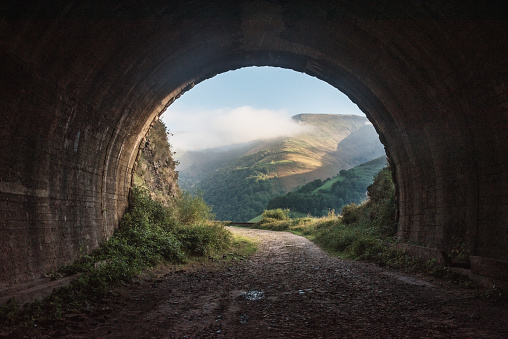 Light at the end of the tunnel concept - An old, dark tunnel leading to a beautiful landscape