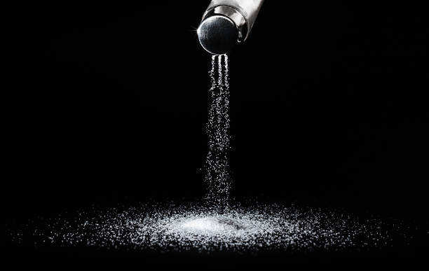 Salt shaker on a dark background Salt spills out of the salt shaker in thin streams on a black background.Concept salting/ salt seasoning stock pictures, royalty-free photos & images