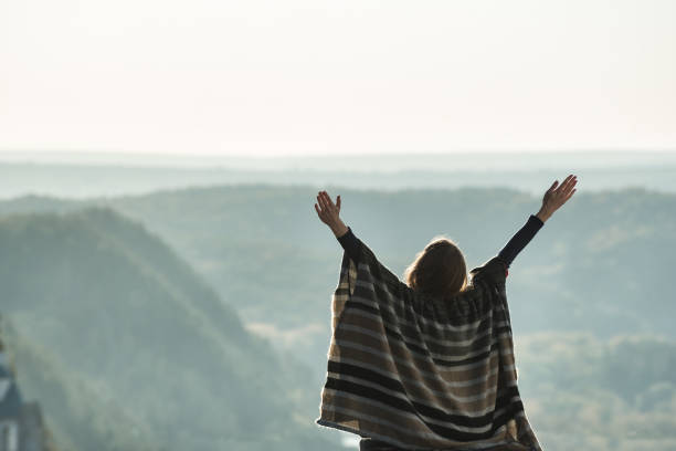 istock Young woman enjoying sunny day on a hill. Raised hands. Back view 1178074513