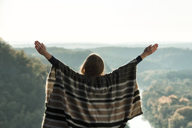 istock Young woman enjoying sunny day on a hill. Raised hands. Back view 1178074566