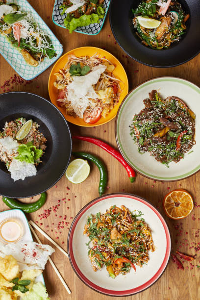Above view background of delicious Asian food set on wooden table decorated with chili pepper and lime, copy space
