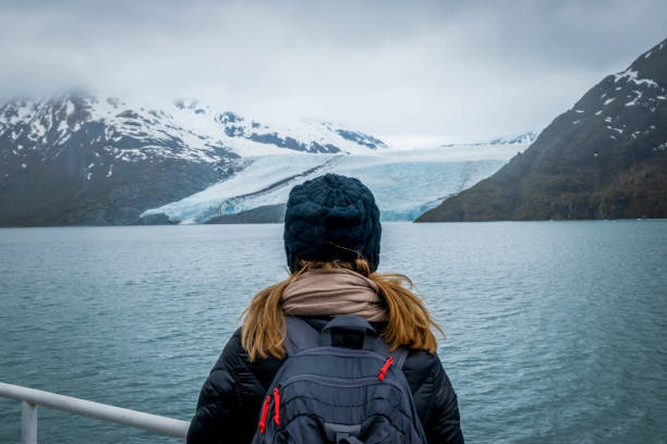 Woman looking at mountain range and glacier. Woman doing a cruise and looking at the Portage glacier in Alaska with snowcapped mountains in background. glacier photos stock pictures, royalty-free photos & images