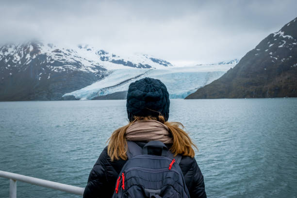 Woman looking at mountain range and glacier. Woman doing a cruise and looking at the Portage glacier in Alaska with snowcapped mountains in background. broken spring stock pictures, royalty-free photos & images