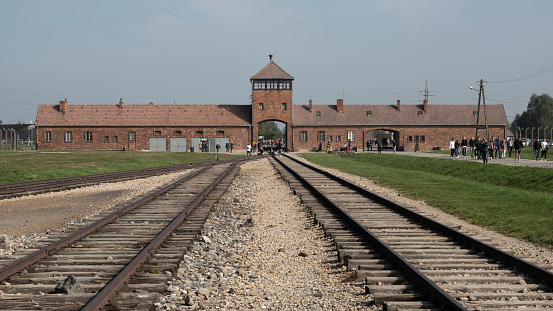 Oswiecim, Poland - 24th Sep 2019: Railway tracks and entrance building at Auschwitz-Birkenau concentration and extermination camp near Oswiecim in Poland.  Now an historical monument, it is estimated that over a million Jewish people, Polish people, Soviet POWs and other ethnic groups were murdered here by the Nazis between 1940 and 1945.