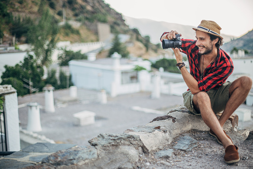 Handsome hipster photographer with digital camera in Spanish village