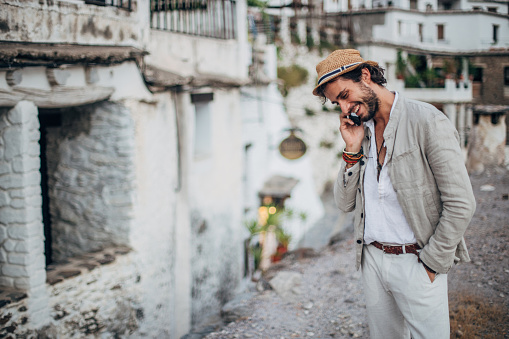 Handsome hipster man talking on mobile phone in some Spanish village