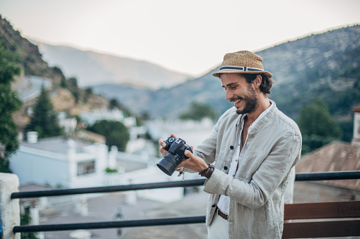 Handsome hipster tourist photographer with digital camera in Spanish village