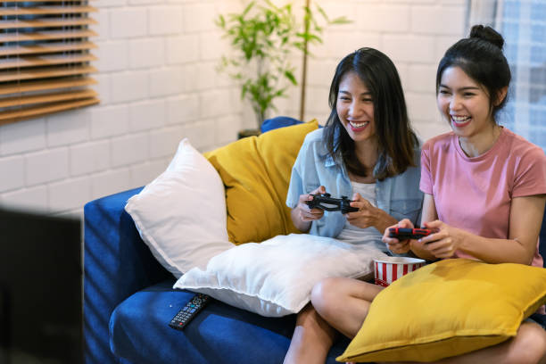 若いアジアの女性や友人の率直なビデオゲームを楽しく笑い、楽しさとコピースペースと一緒にソファに座って。若いアジアの女の子の友人や家族の姉妹のゲーム競争。 - bff ストックフォトと画像