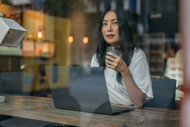 istock Chinese woman drinking coffee and working in cafe on laptop 1178084351