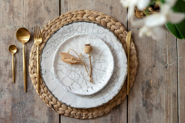 istock Flat lay and top view of table setting on wooden background. White plates, tableware, cutlery spoon with fork, knife lying on woven rug with decorative elements and fresh orchid flower 1178084757