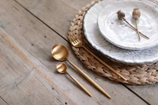 istock High angle view of holiday table setting on wooden background with copy space. White plates, tableware and cutlery spoon with fork, knife lying on woven mat with decorative poppy flower 1178084848
