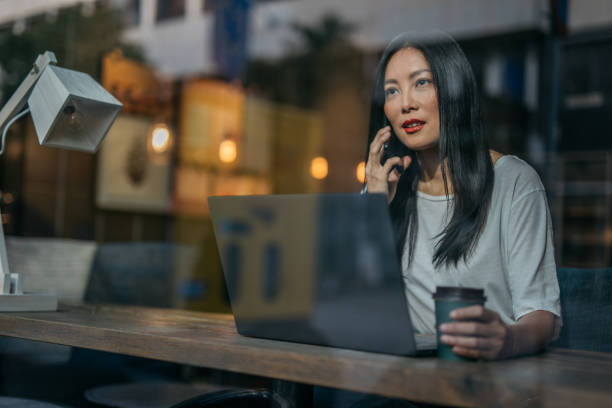 istock Chinese woman drinking coffee and working in cafe on computer 1178084894