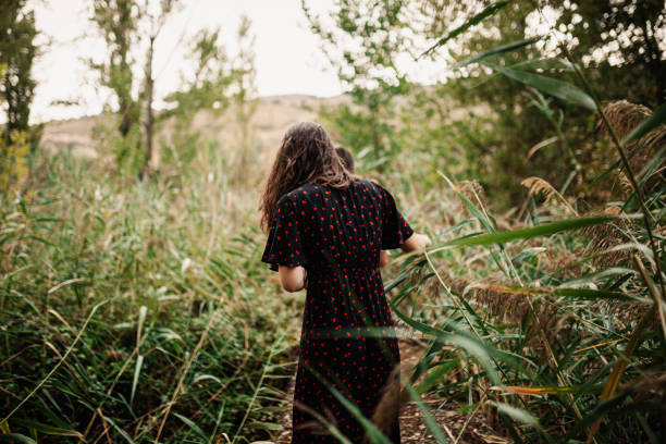 istock Back view of two young women walking through the field 1178086992