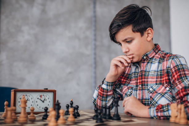 chico inteligente jugando ajedrez - chess skill concentration intelligence fotografías e imágenes de stock