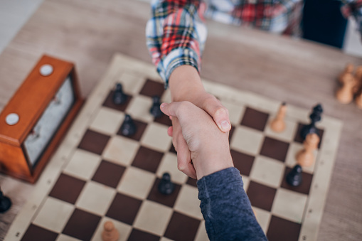 Two young boys, playing chess in school of chess,  handshake after a chess game.