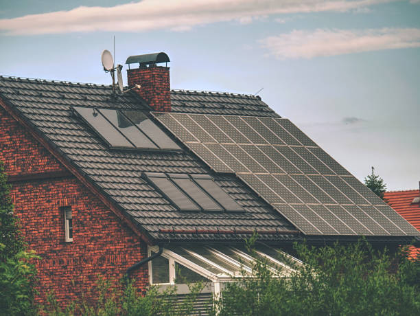 Family house with solar panels on the roof against blue sky stock photo