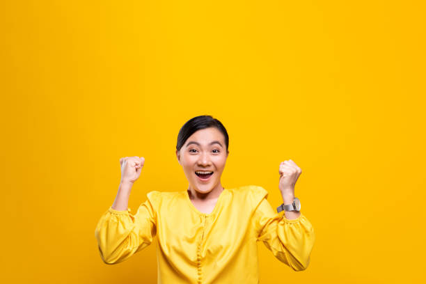 istock Happy woman make winning gesture isolated over yellow background 1178094180