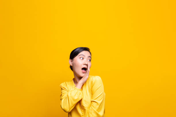 istock Woman make gossip gesture isolated over yellow background 1178094190