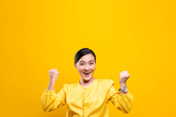 istock Happy woman make winning gesture isolated over yellow background 1178095001