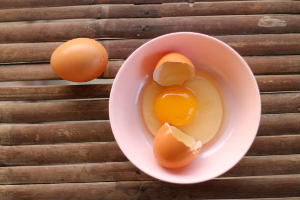 istock shell with egg and open Eggs in a pink bowl on Bamboo battens. Top view closeup 1178095524